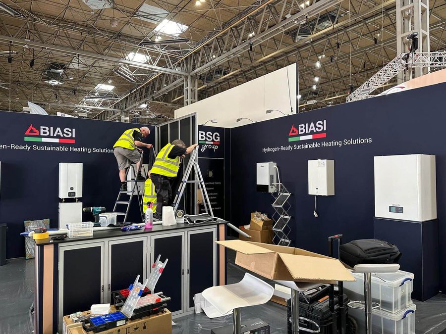 Three men constructing the Installer show Biasi stand. They are wearing high vis jackets and are up ladders.