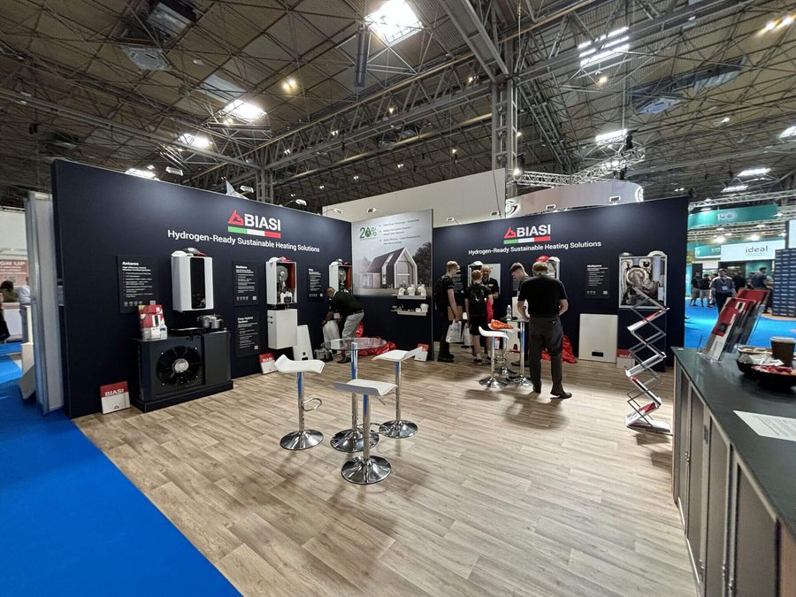 Biasi stand at the installer show which has boilers mounted on the wall, hardwood floor and biais team members having a meeting. Stalls and high tables are in the centre.