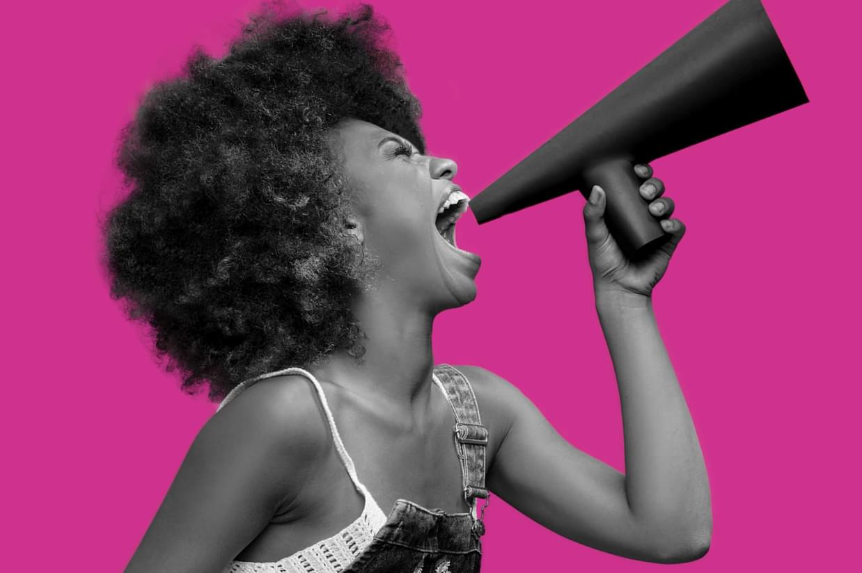 Woman shouting through a bullhorn on a plain pink background