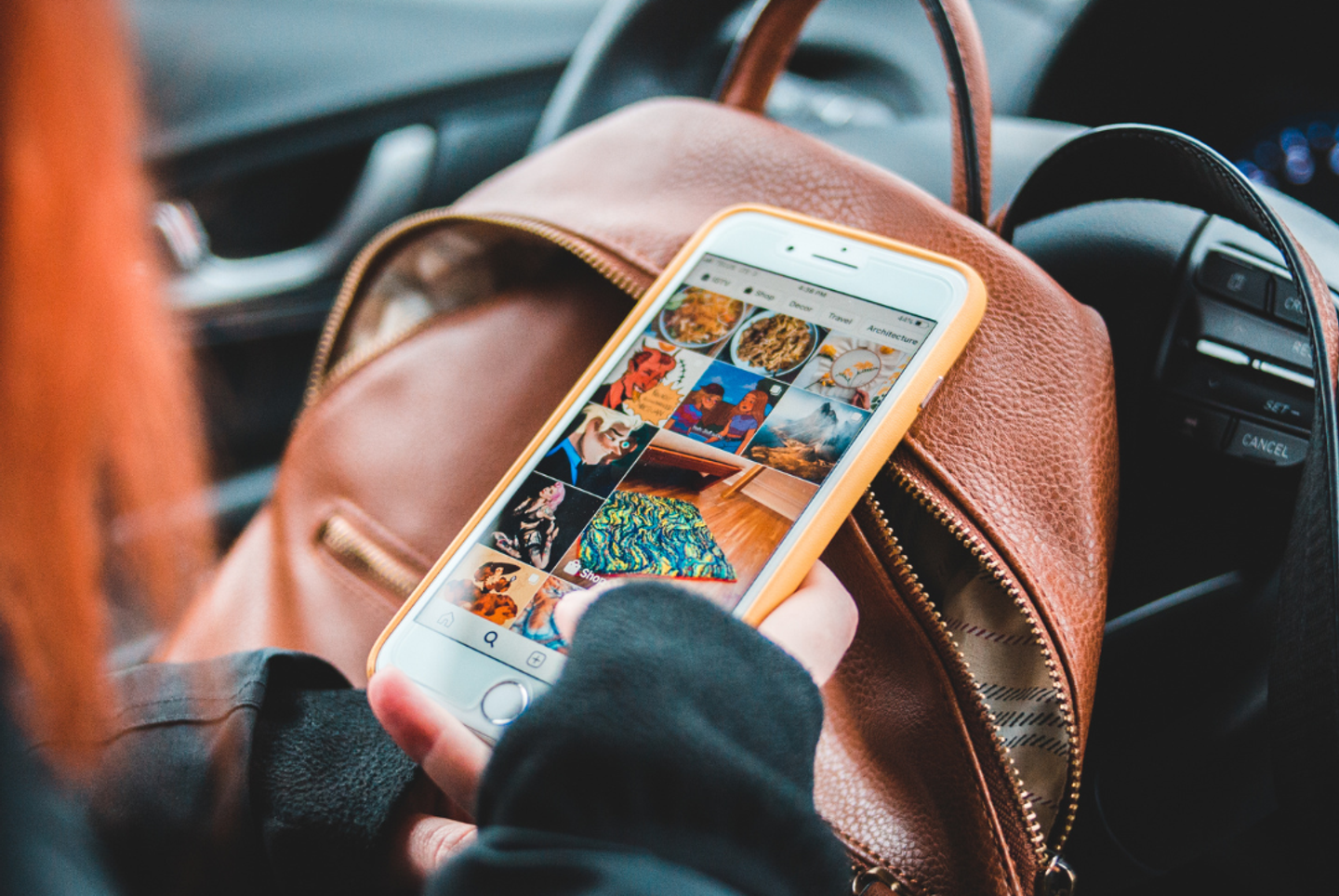 A phone rested upon a backpack in a woman's lap, displaying a social media feed with generic content and product options