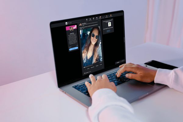 A desk with a laptop scrolling through Emma's LinkedIn profile, the background is white with a magenta and purple hue from lights in the room