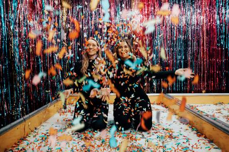 2 women throwing colourful confetti
