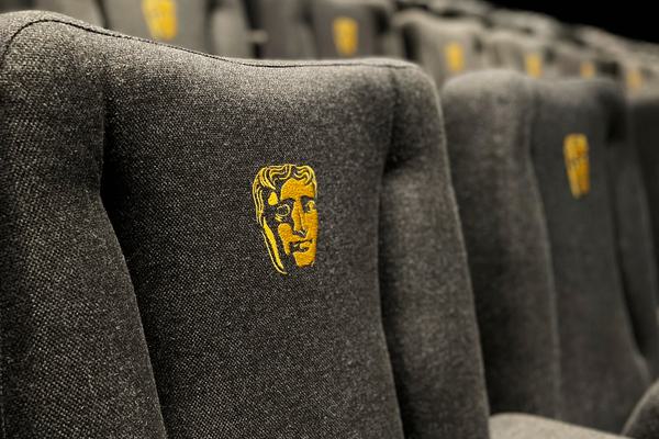 Multiple rows of cinema seats blurring into the distance. Each seat contains the BAFTA mask emblem.