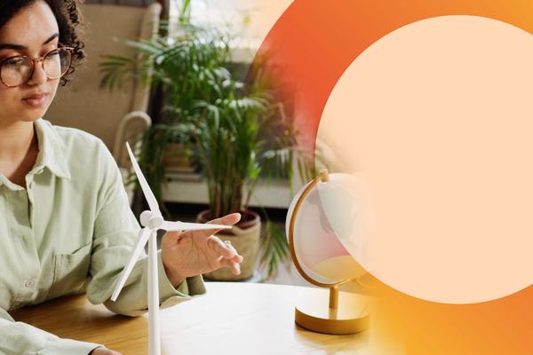A woman spinning a model wind turbine with her finger