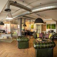 An image of a newly refurbished office featuring green leather arm chairs in a modern space with wooden flooring.