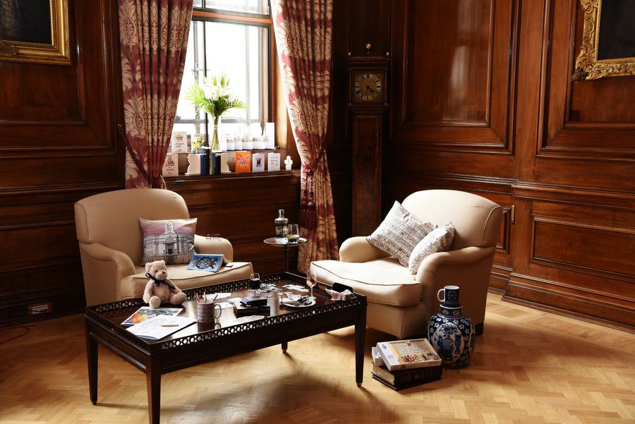 Two sofa seats and table with various items on in a wood panelled room