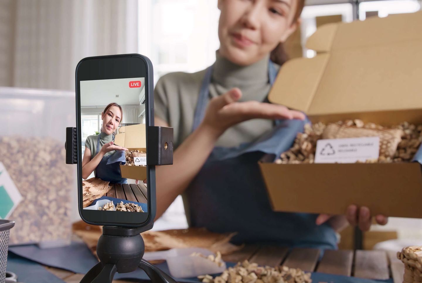 An image of a phone recording a woman presenting a sustainable product's packaging process