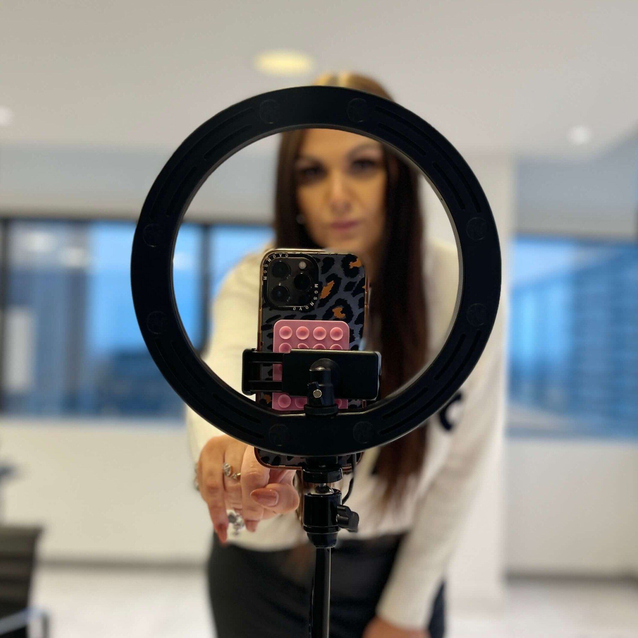 Image of ring light stand containing a phone from the view of somebody who is being recorded