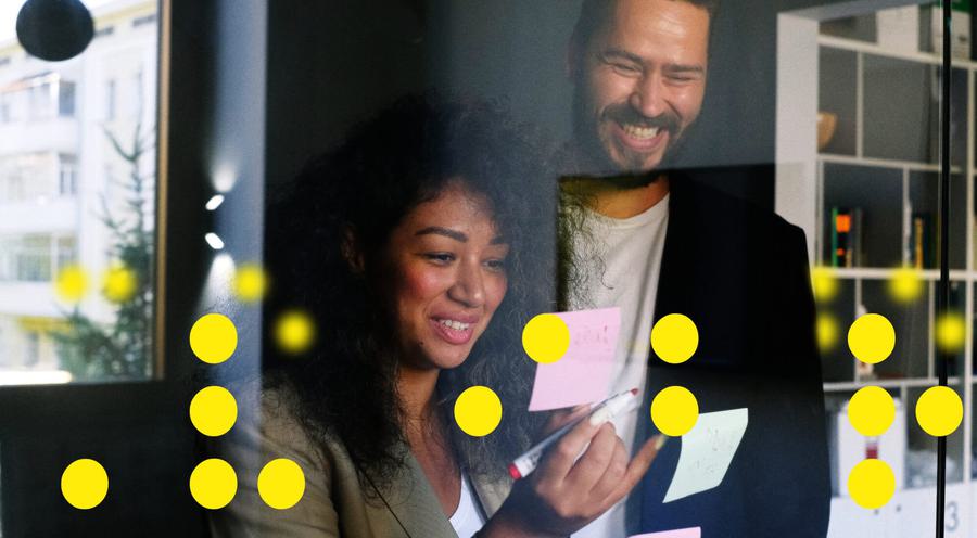 Male and female co-workers writing on post-it notes.