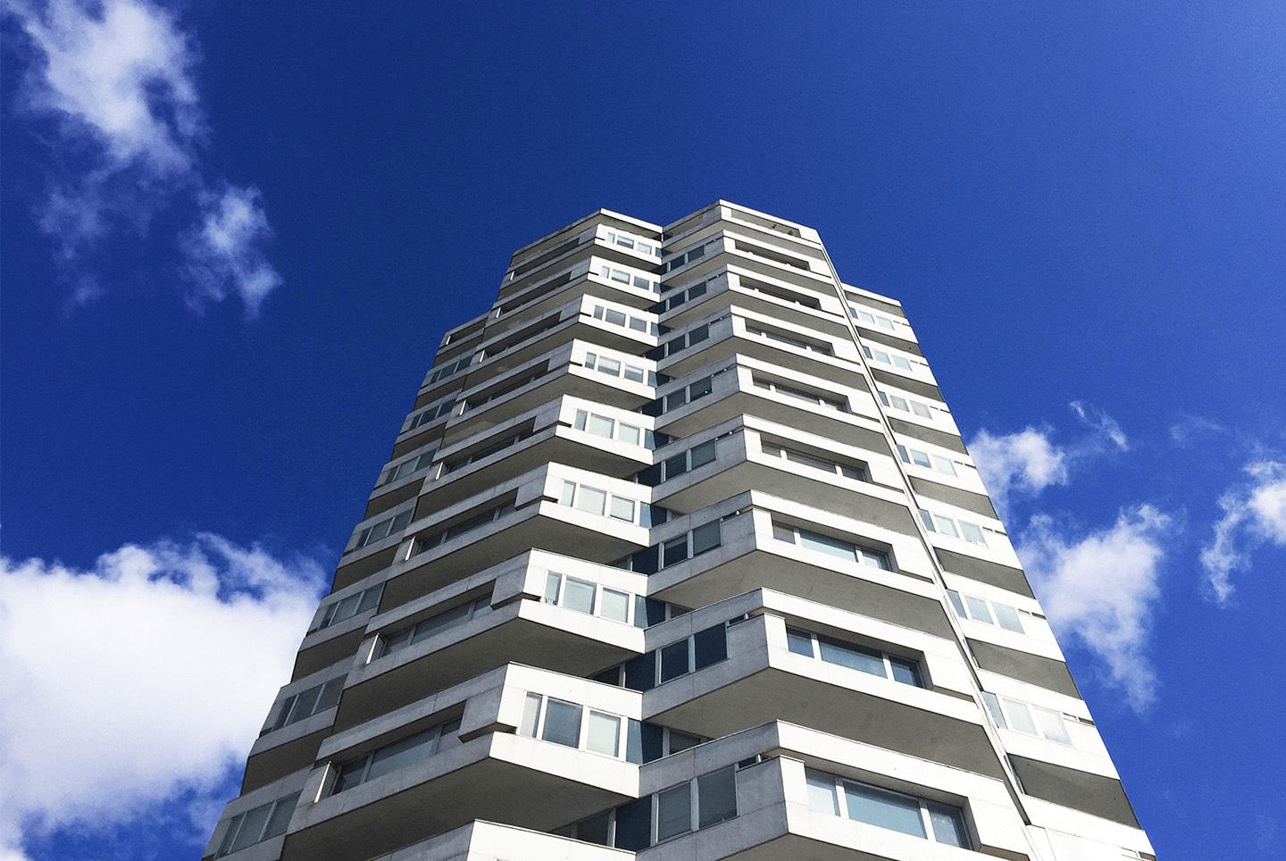 The distinctive One Croydon building shown on a bright blue skyline with a few white fluffy clouds