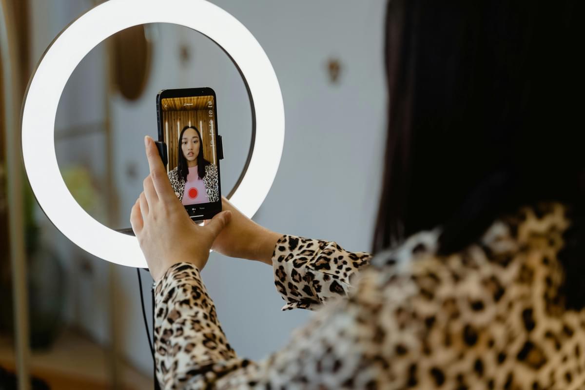 A woman taking a selfie in front of a ring light