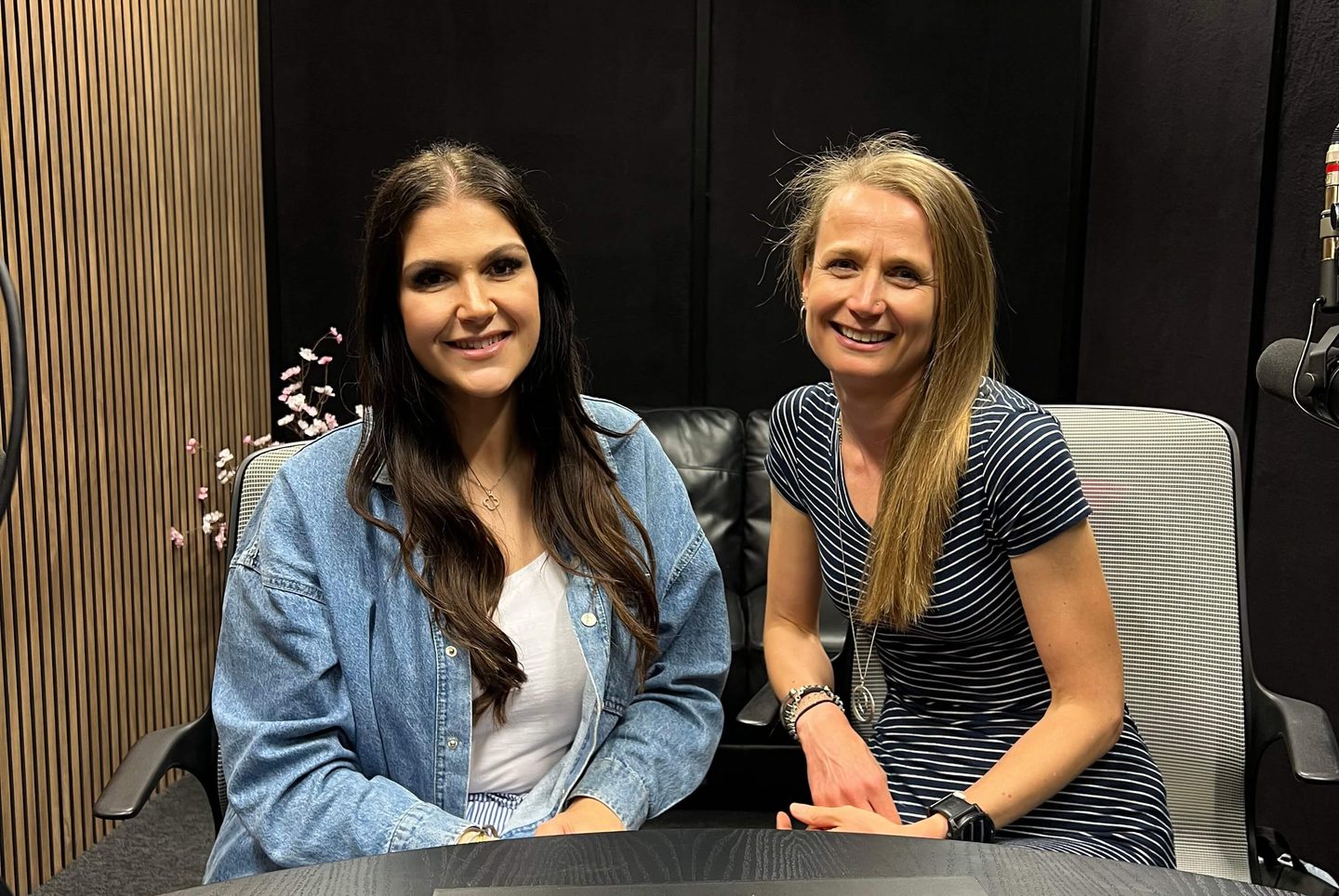 An image of Emma and Ally Whitlock sat in a podcast studio with a small 'On air' sign on the table'