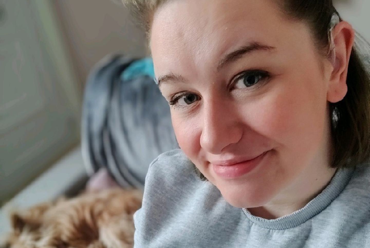 Selfie taken by Lily, who is smiling at the camera. She has dark hair and is wearing a grey sweater.