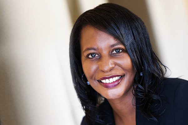 Professional headshot of Monica Beckles. Monica has dark hair and brown eyes. She is wearing a black jacket.